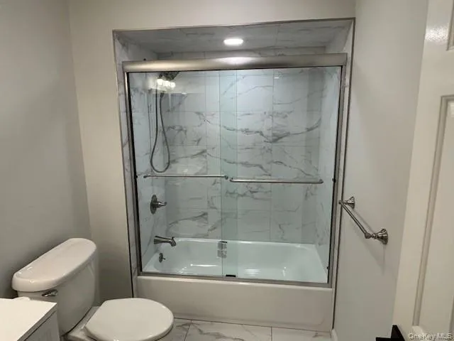 Bathroom featuring shower / bath combination with glass door, marble look tile flooring, and vanity Bathroom featuring shower / bath combination with glass door, marble look tile flooring, and vanity