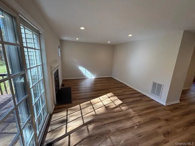 Spare room with recessed lighting, dark wood-style flooring, and a fireplace Spare room with recessed lighting, dark wood-style flooring, and a fireplace