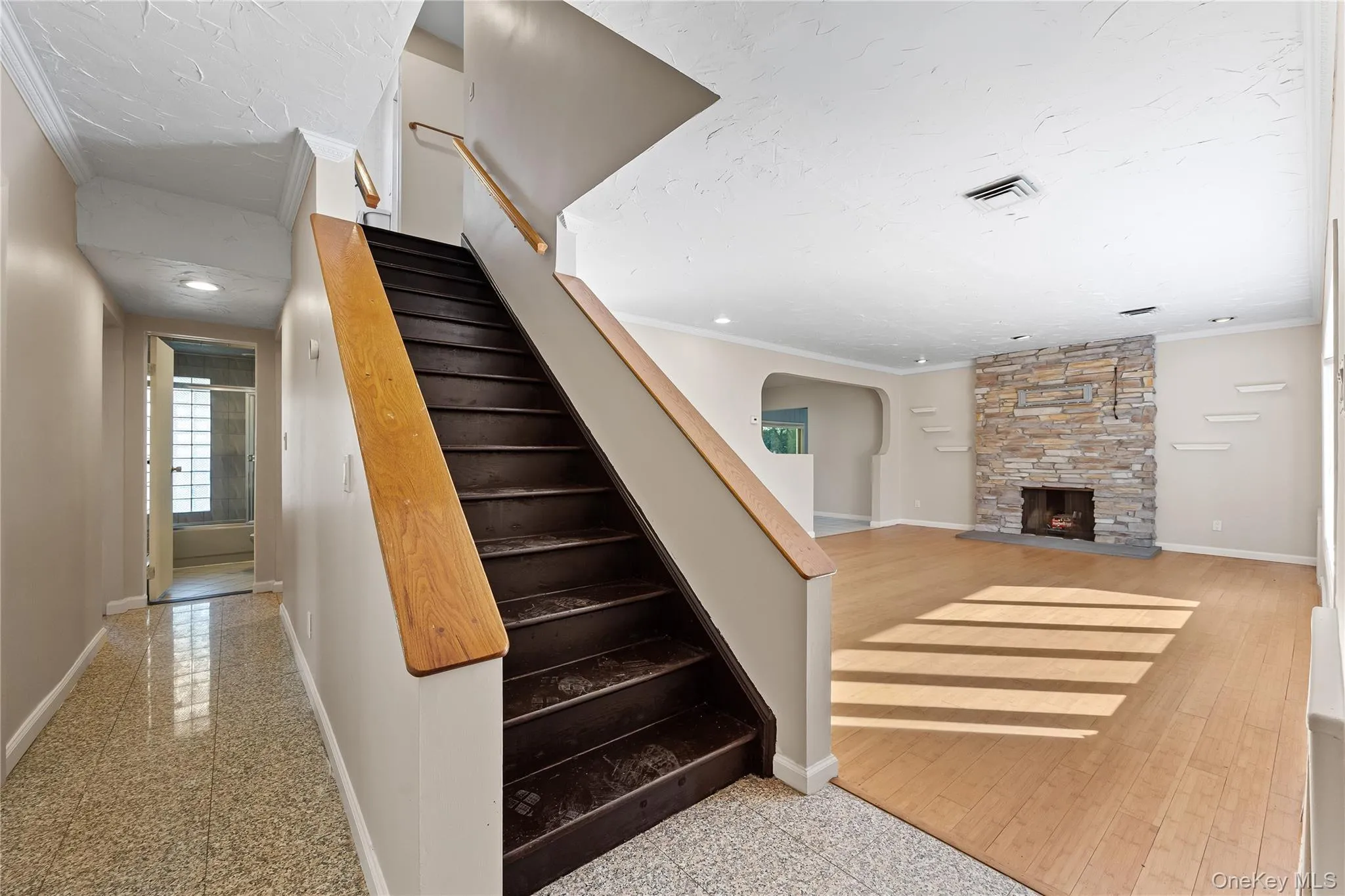 Staircase with ornamental molding, a stone fireplace, arched walkways, and granite tiled floors Staircase with ornamental molding, a stone fireplace, arched walkways, and granite tiled floors