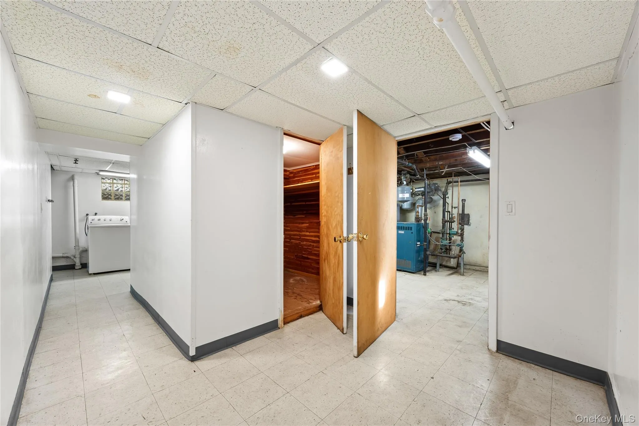 Corridor featuring light flooring, washer / clothes dryer, and a heating unit Corridor featuring light flooring, washer / clothes dryer, and a heating unit