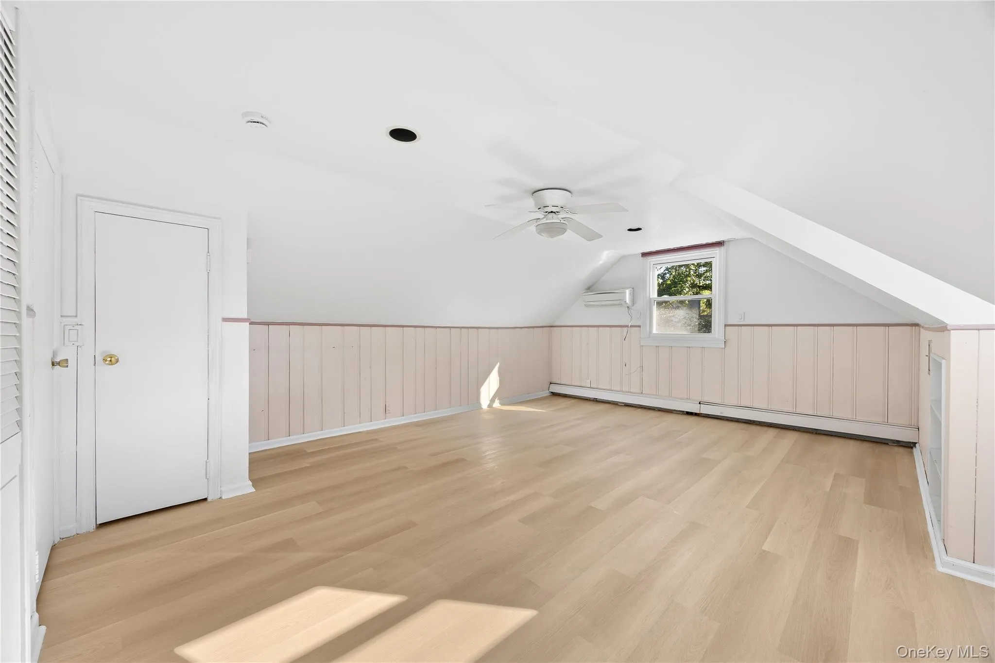 Bonus room featuring vaulted ceiling, light wood-style floors, a baseboard heating unit, ceiling fan, and a wainscoted wall Bonus room featuring vaulted ceiling, light wood-style floors, a baseboard heating unit, ceiling fan, and a wainscoted wall