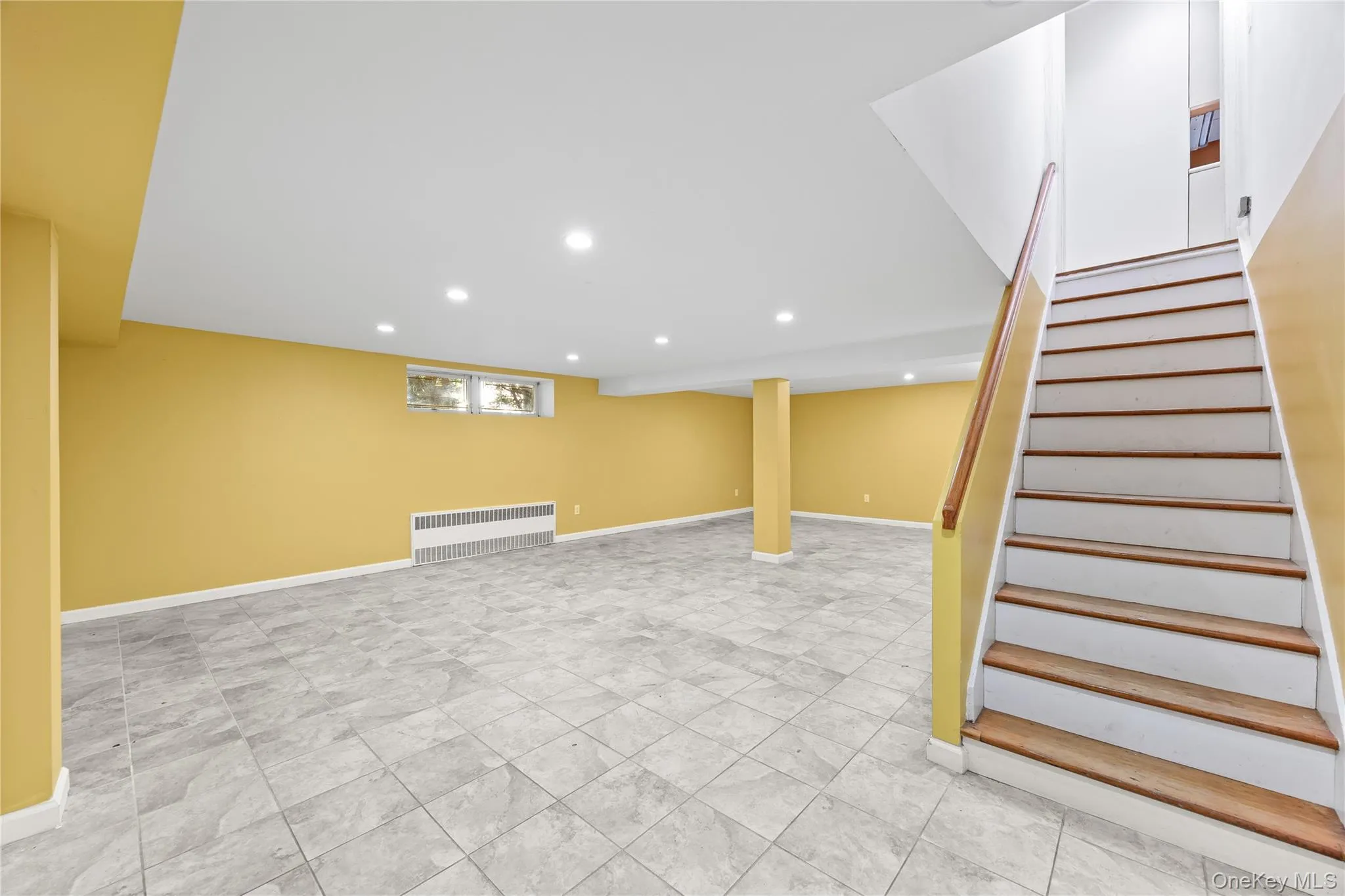 Basement with recessed lighting, radiator heating unit, and stairs Basement with recessed lighting, radiator heating unit, and stairs