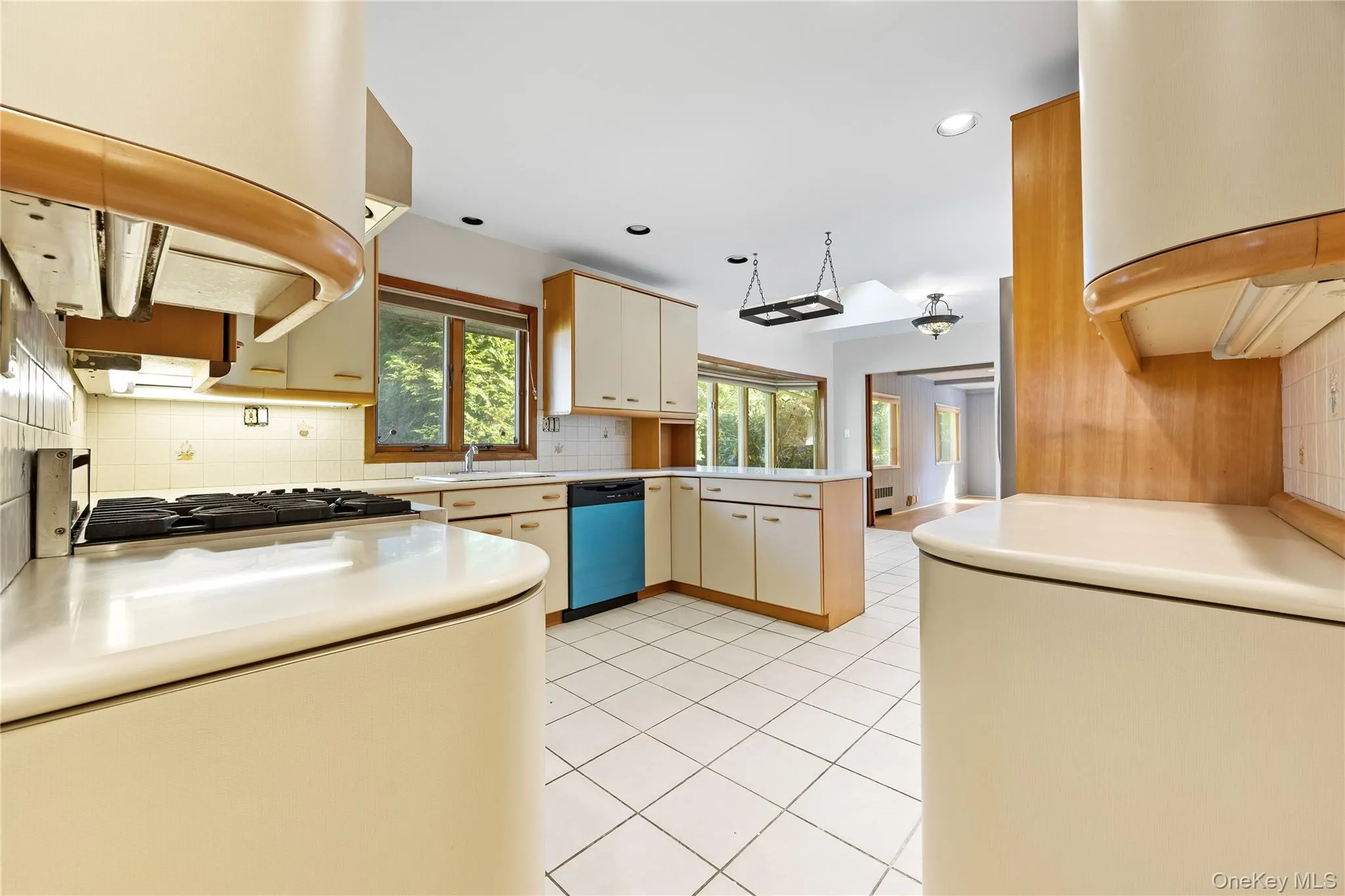 Kitchen with backsplash, light tile patterned floors, light countertops, dishwashing machine, and recessed lighting Kitchen with backsplash, light tile patterned floors, light countertops, dishwashing machine, and recessed lighting