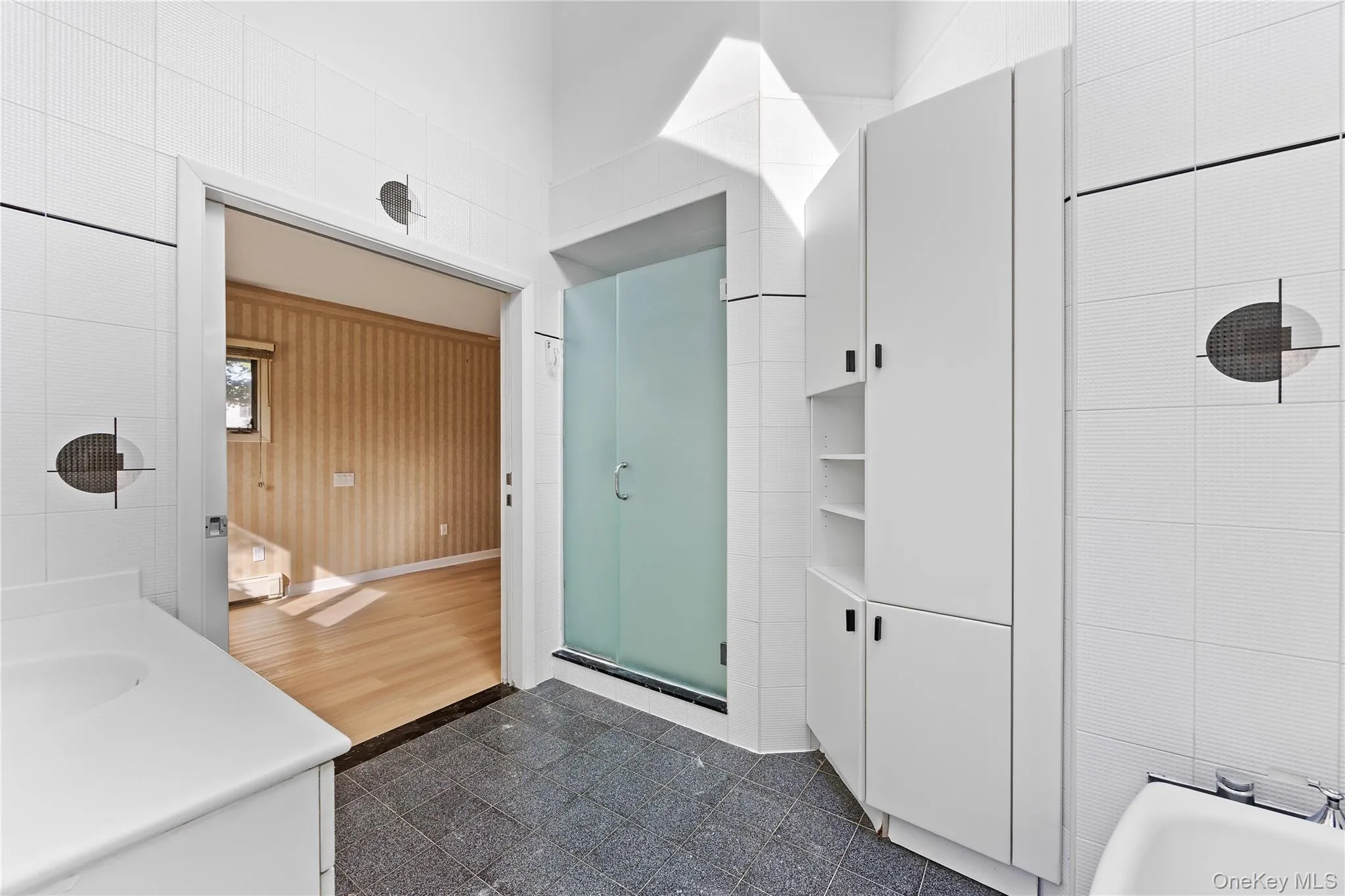 Bathroom featuring vanity, tile walls, and enclosed tub / shower combo Bathroom featuring vanity, tile walls, and enclosed tub / shower combo