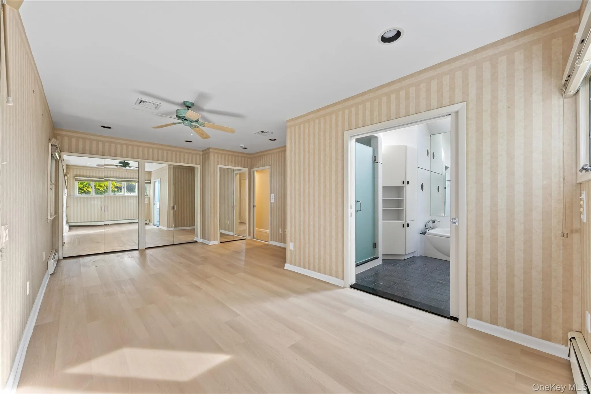 Unfurnished room with wallpapered walls, light wood finished floors, a baseboard radiator, crown molding, and a ceiling fan Unfurnished room with wallpapered walls, light wood finished floors, a baseboard radiator, crown molding, and a ceiling fan