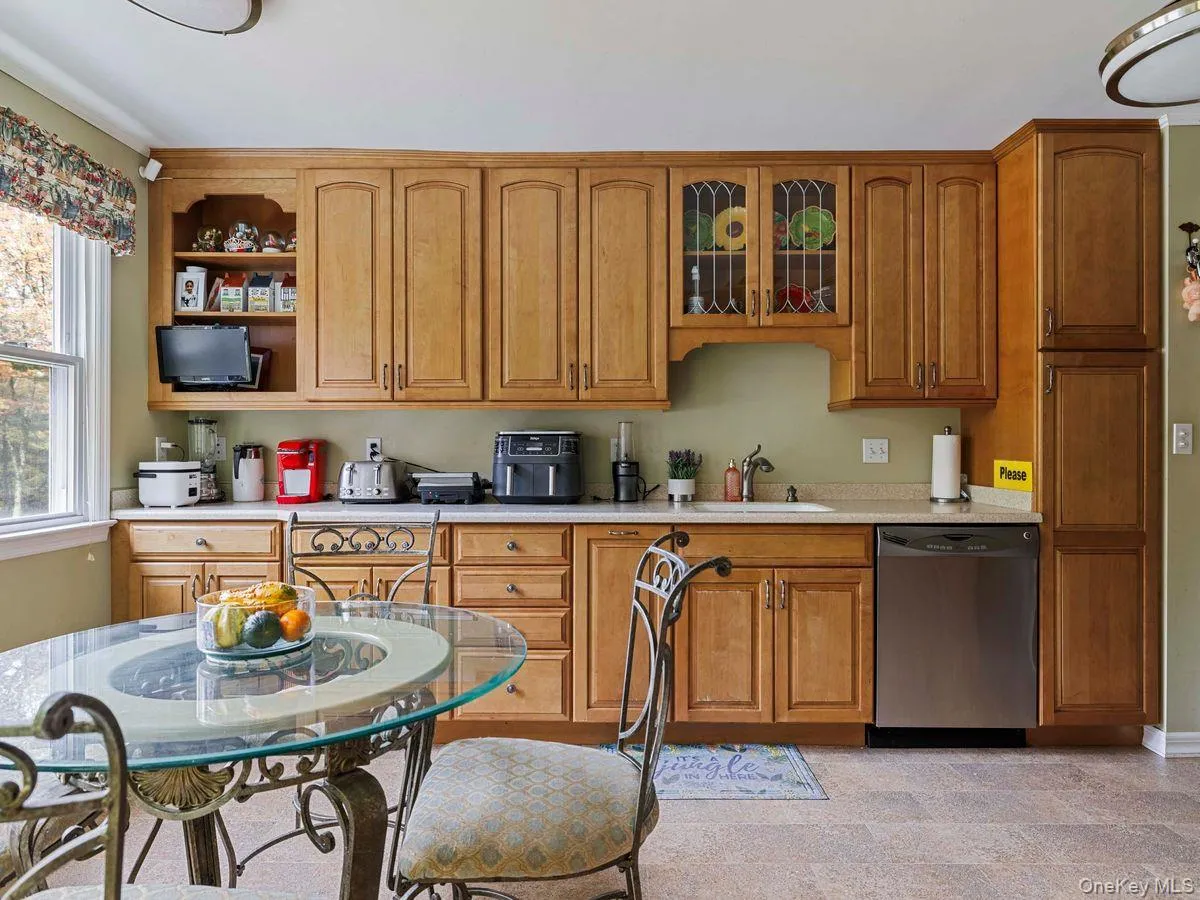 Kitchen with stainless steel dishwasher, brown cabinets, glass insert cabinets, and open shelves Kitchen with stainless steel dishwasher, brown cabinets, glass insert cabinets, and open shelves