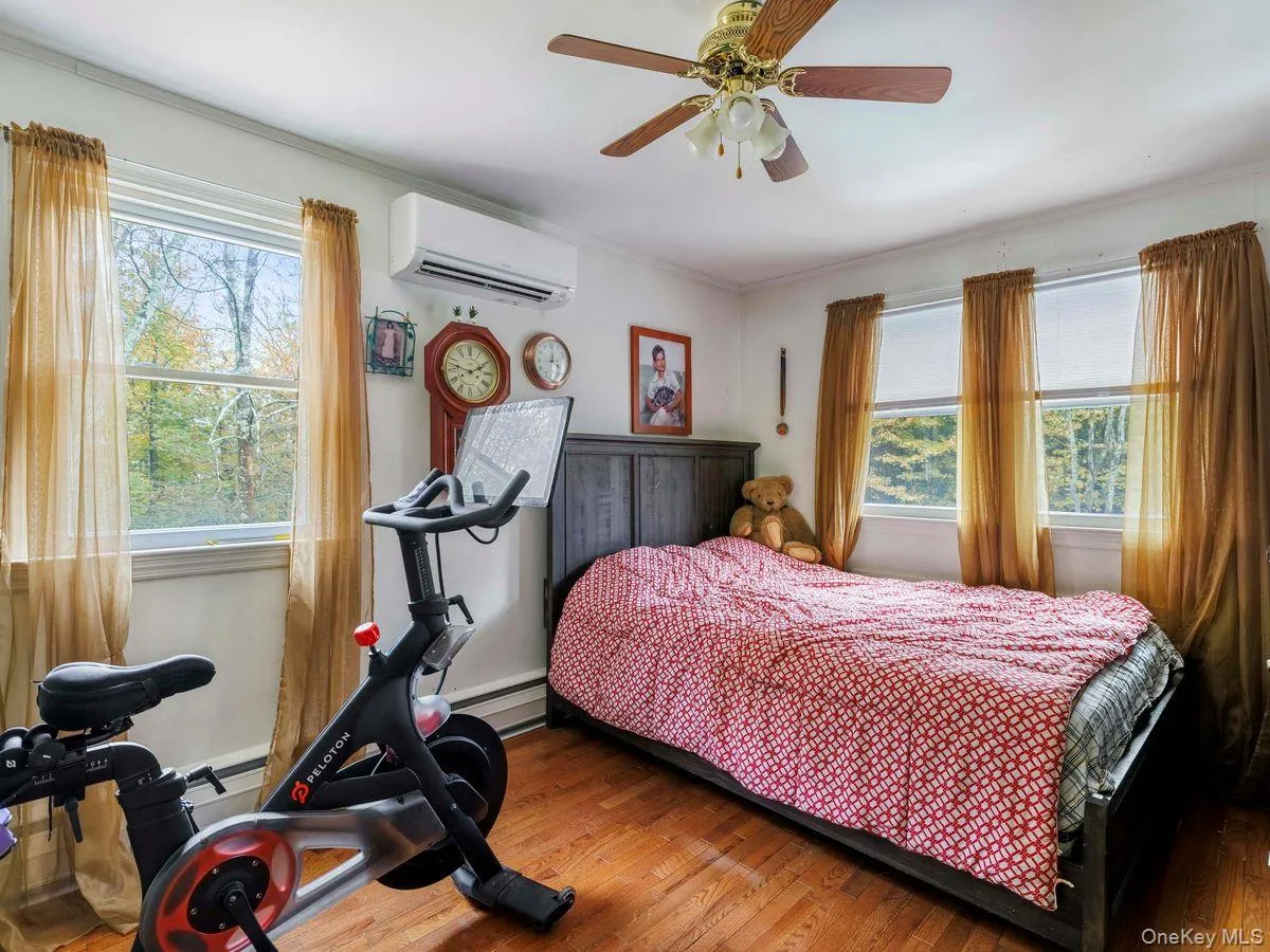 Bedroom with wood finished floors, a wall mounted AC, ceiling fan, baseboard heating, and ornamental molding Bedroom with wood finished floors, a wall mounted AC, ceiling fan, baseboard heating, and ornamental molding