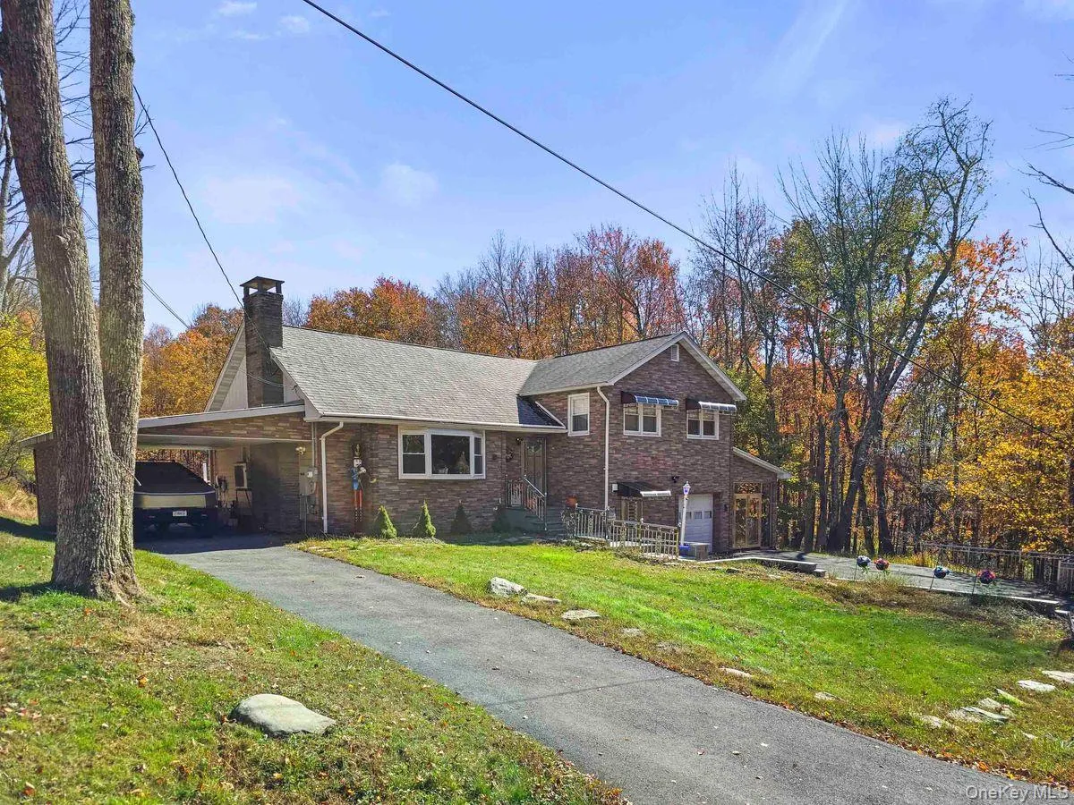 View of front of house with a front lawn, a chimney, a carport, driveway, and brick siding View of front of house with a front lawn, a chimney, a carport, driveway, and brick siding
