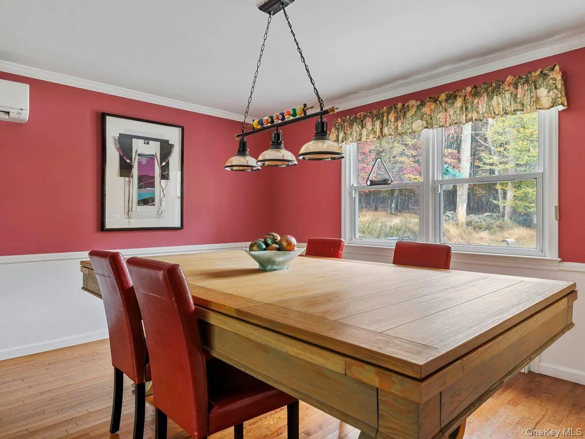 Dining area featuring light wood-style flooring, crown molding, and a wall mounted AC Dining area featuring light wood-style flooring, crown molding, and a wall mounted AC