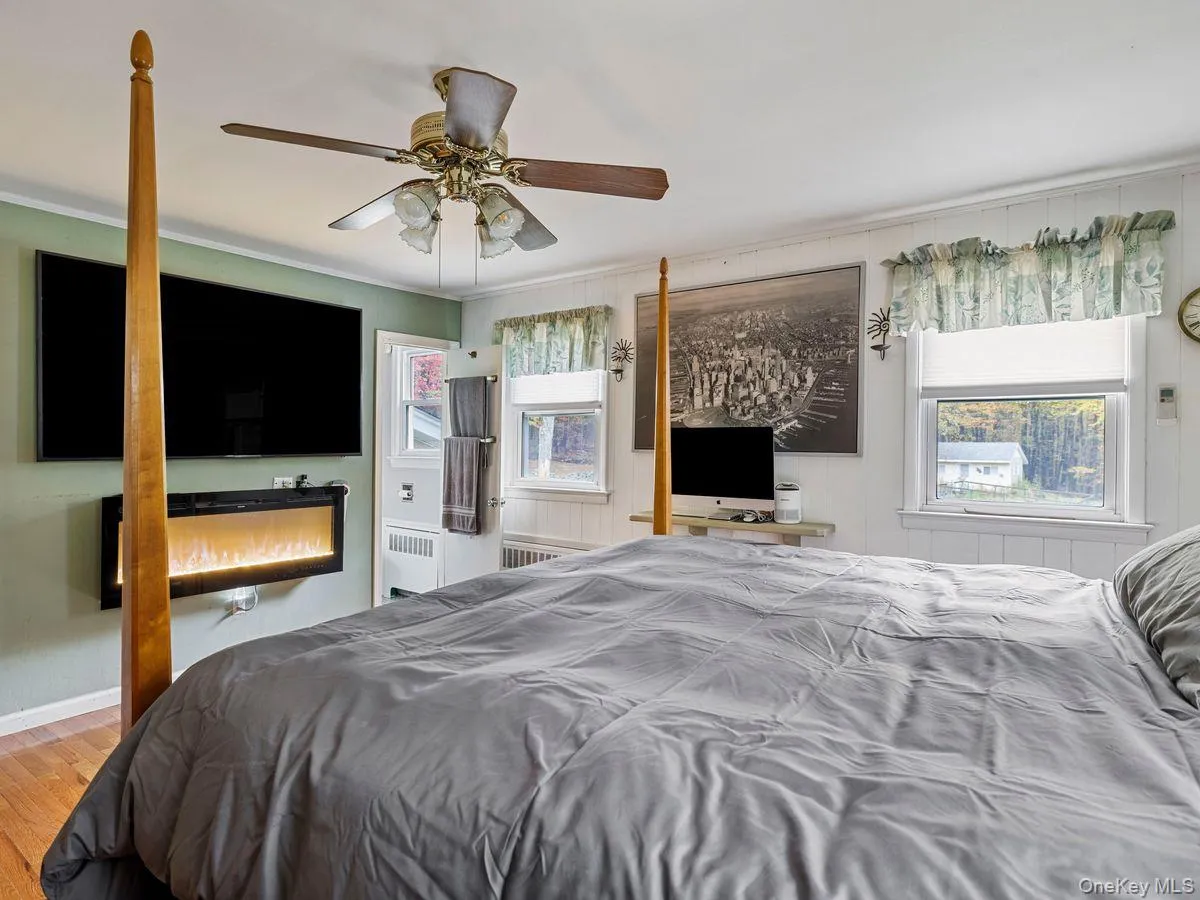 Bedroom with crown molding, radiator heating unit, a ceiling fan, wood finished floors, and multiple windows Bedroom with crown molding, radiator heating unit, a ceiling fan, wood finished floors, and multiple windows