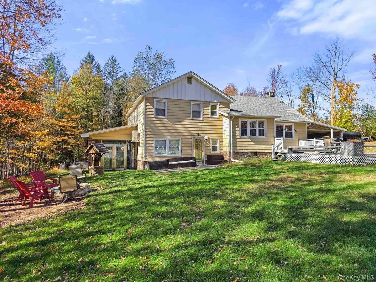 Back of house featuring a lawn, a deck, a hot tub, a patio area, and a fire pit Back of house featuring a lawn, a deck, a hot tub, a patio area, and a fire pit