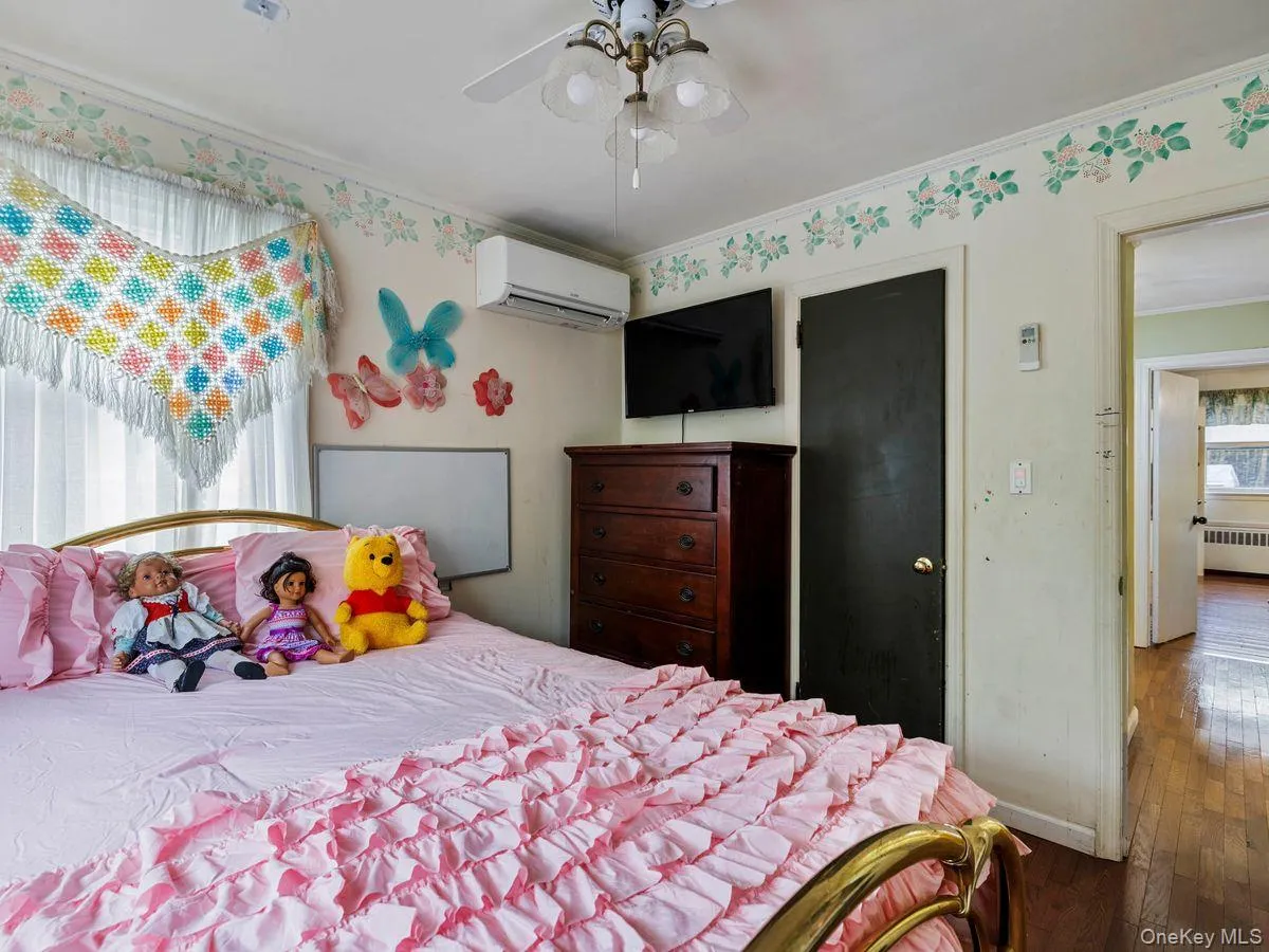 Bedroom featuring ornamental molding, hardwood / wood-style floors, radiator, a ceiling fan, and a wall unit AC Bedroom featuring ornamental molding, hardwood / wood-style floors, radiator, a ceiling fan, and a wall unit AC