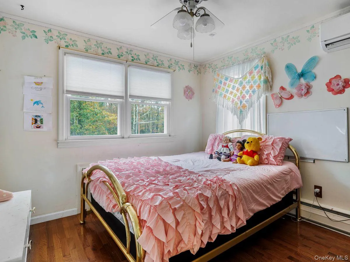 Bedroom featuring ornamental molding, dark wood-style floors, a wall mounted air conditioner, a ceiling fan, and a baseboard heating unit Bedroom featuring ornamental molding, dark wood-style floors, a wall mounted air conditioner, a ceiling fan, and a baseboard heating unit