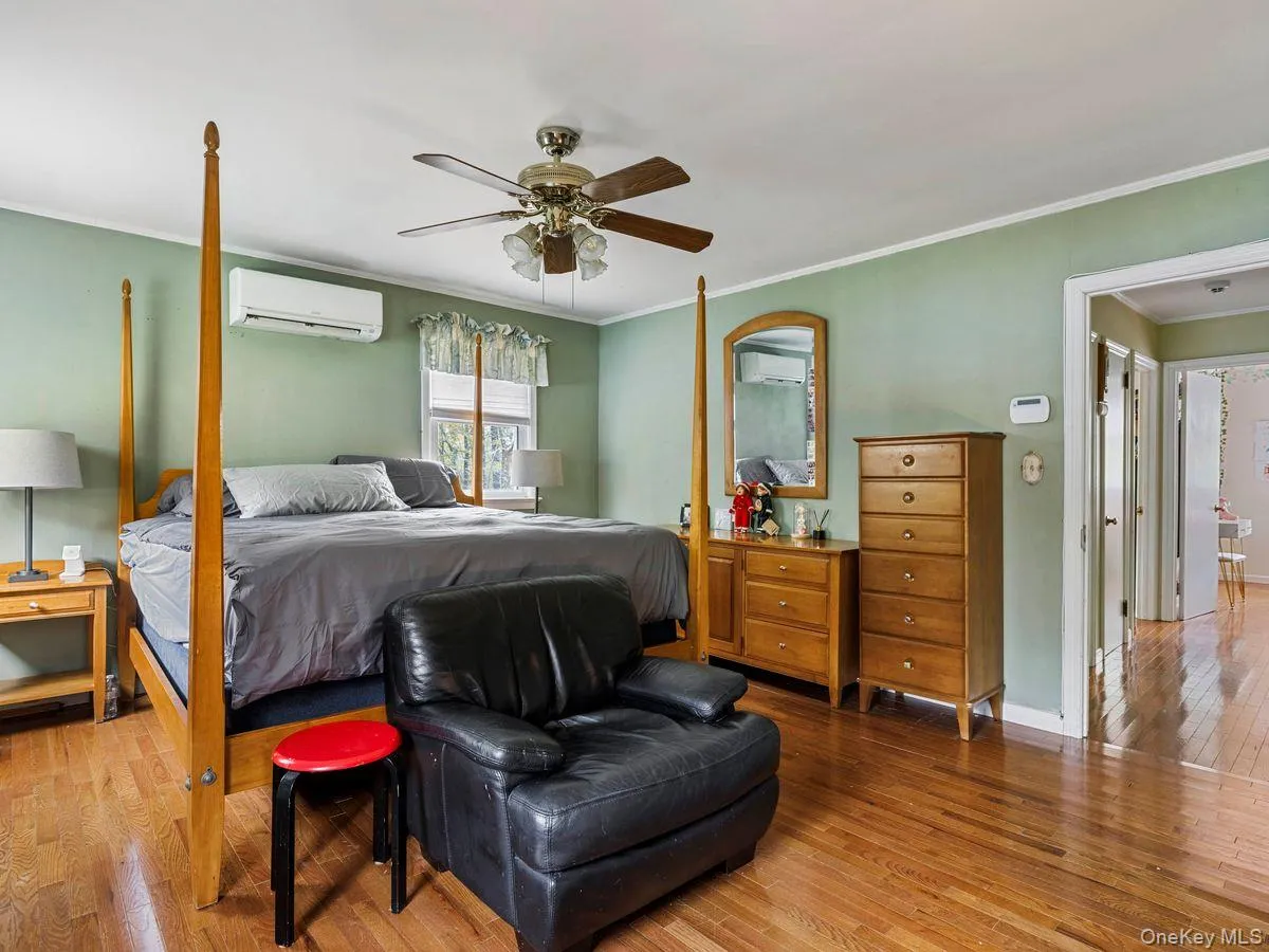 Bedroom with crown molding, wood-type flooring, ceiling fan, and a wall mounted air conditioner Bedroom with crown molding, wood-type flooring, ceiling fan, and a wall mounted air conditioner
