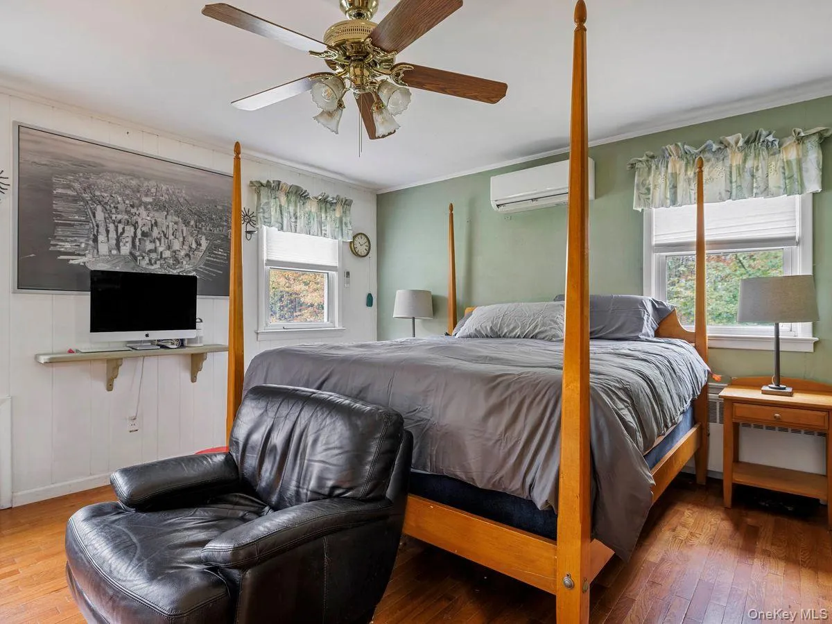 Bedroom featuring hardwood / wood-style flooring, ornamental molding, ceiling fan, and a wall mounted AC Bedroom featuring hardwood / wood-style flooring, ornamental molding, ceiling fan, and a wall mounted AC