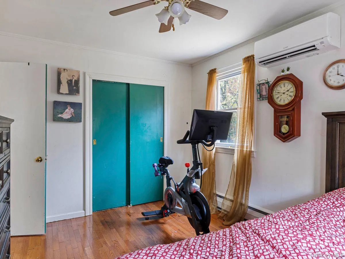 Bedroom with hardwood / wood-style flooring, a wall unit AC, a closet, a ceiling fan, and ornamental molding Bedroom with hardwood / wood-style flooring, a wall unit AC, a closet, a ceiling fan, and ornamental molding