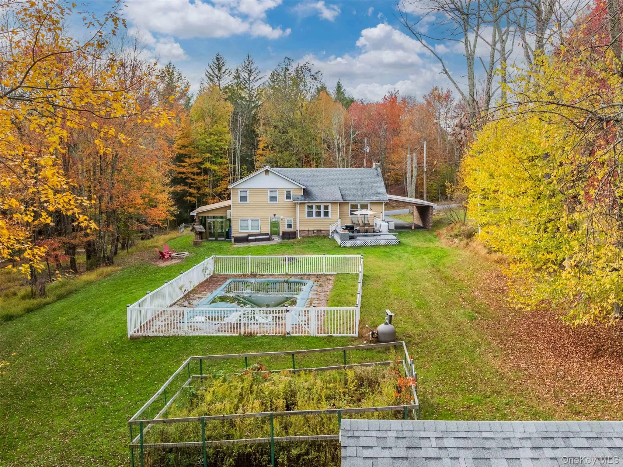 Rear view of house with a vegetable garden, a lawn, a wooded view, and a deck Rear view of house with a vegetable garden, a lawn, a wooded view, and a deck