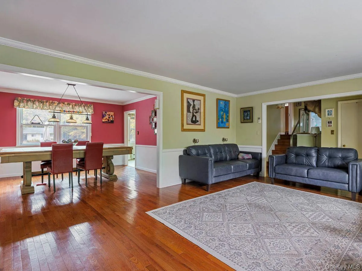 Living room featuring hardwood / wood-style flooring, crown molding, a wainscoted wall, and stairs Living room featuring hardwood / wood-style flooring, crown molding, a wainscoted wall, and stairs