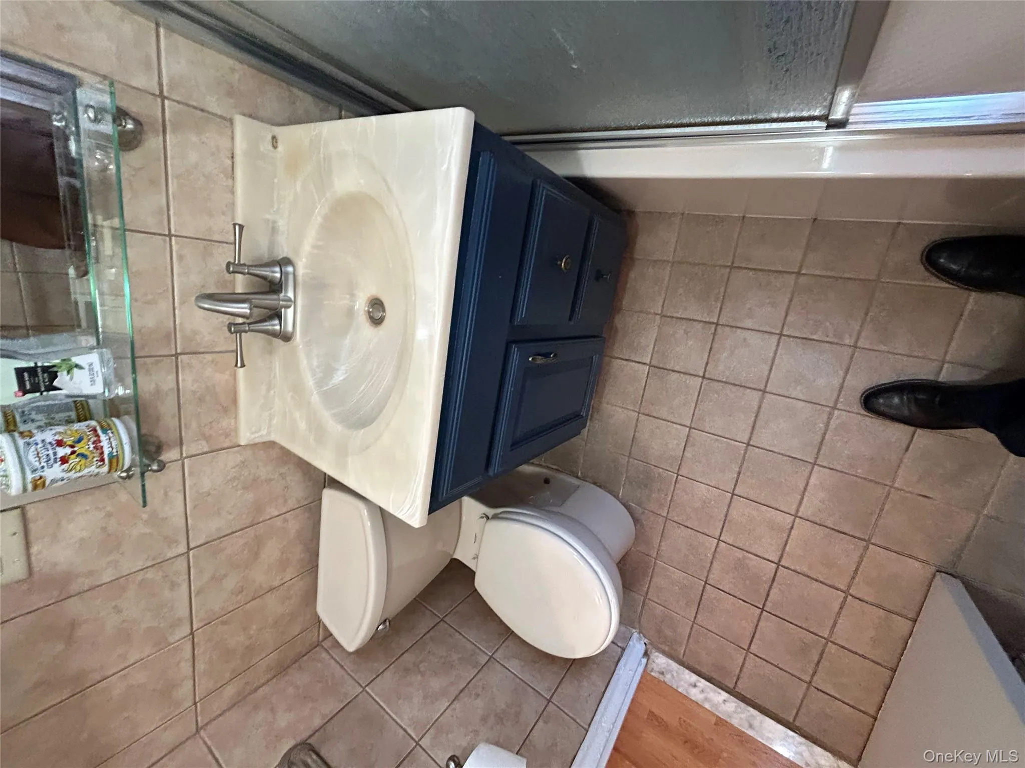 Bathroom with tile walls, vanity, decorative backsplash, and light tile patterned floors Bathroom with tile walls, vanity, decorative backsplash, and light tile patterned floors