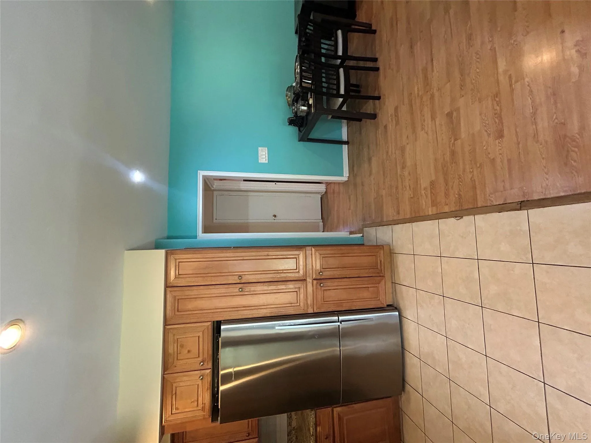 Kitchen with brown cabinets, refrigerator, light wood-style floors, and recessed lighting Kitchen with brown cabinets, refrigerator, light wood-style floors, and recessed lighting