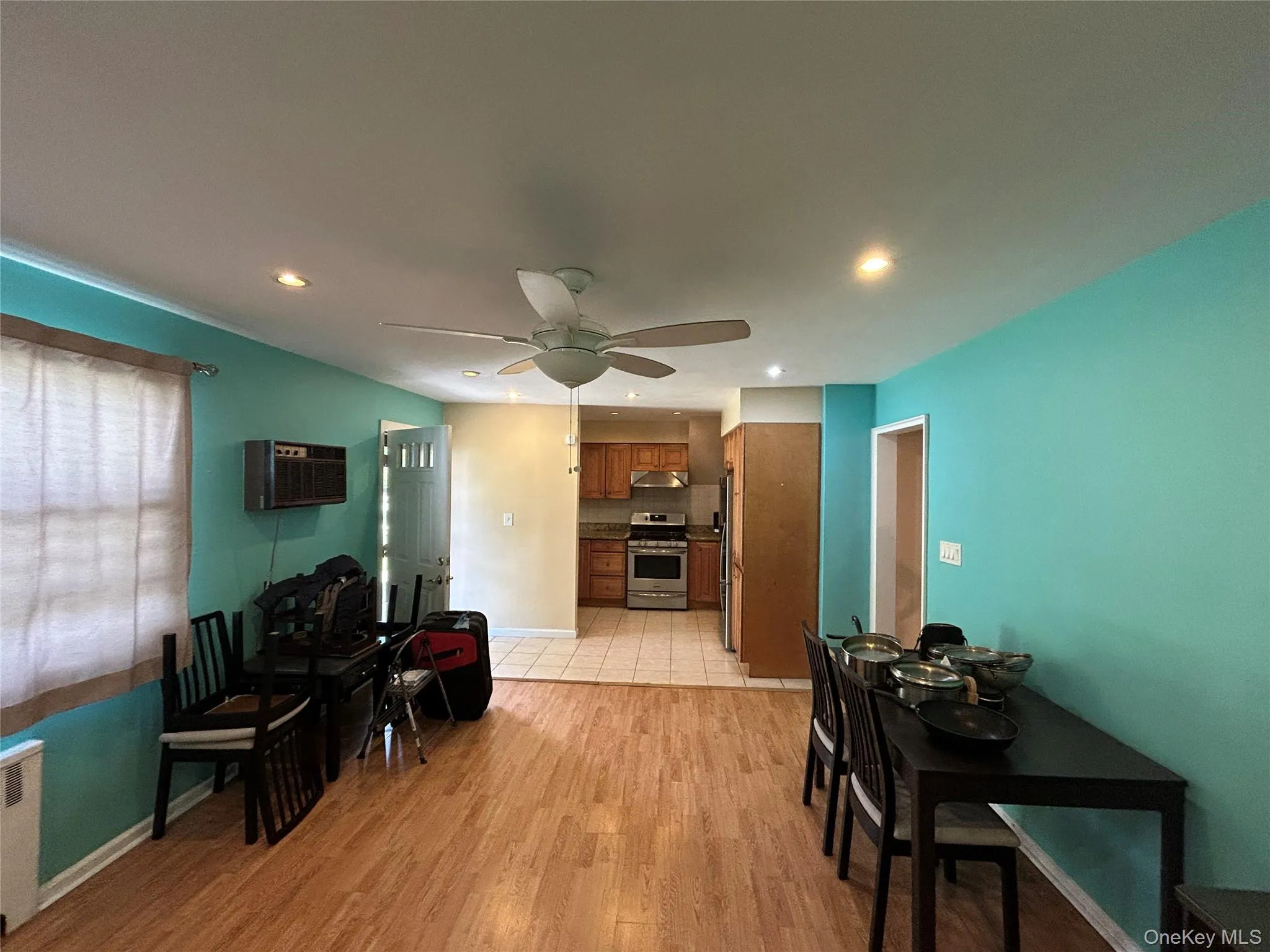 Living area with light wood-style flooring, radiator, recessed lighting, ceiling fan, and a wall unit AC Living area with light wood-style flooring, radiator, recessed lighting, ceiling fan, and a wall unit AC