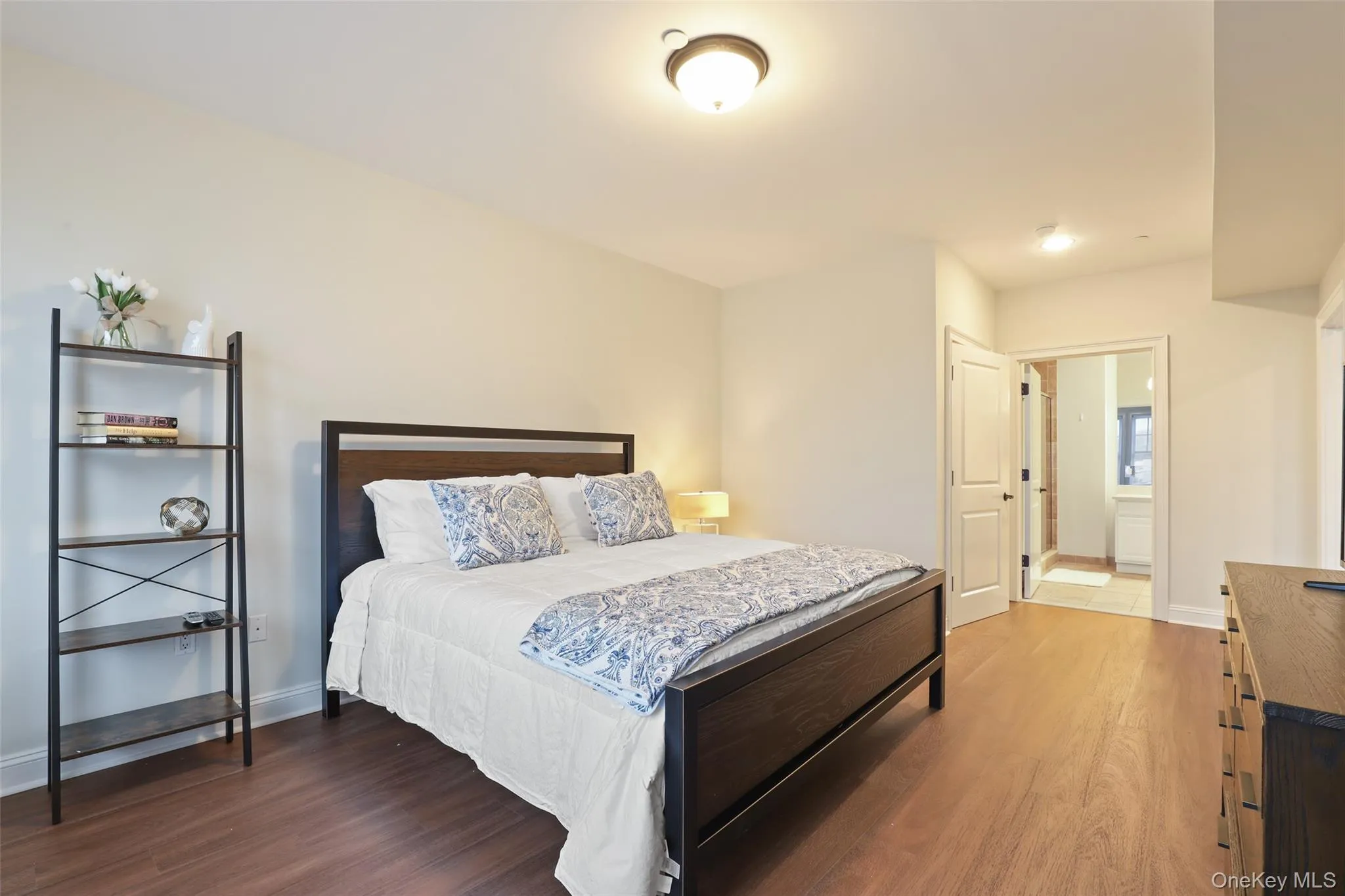 Bedroom featuring wood finished floors, ensuite bath, and baseboards Bedroom featuring wood finished floors, ensuite bath, and baseboards