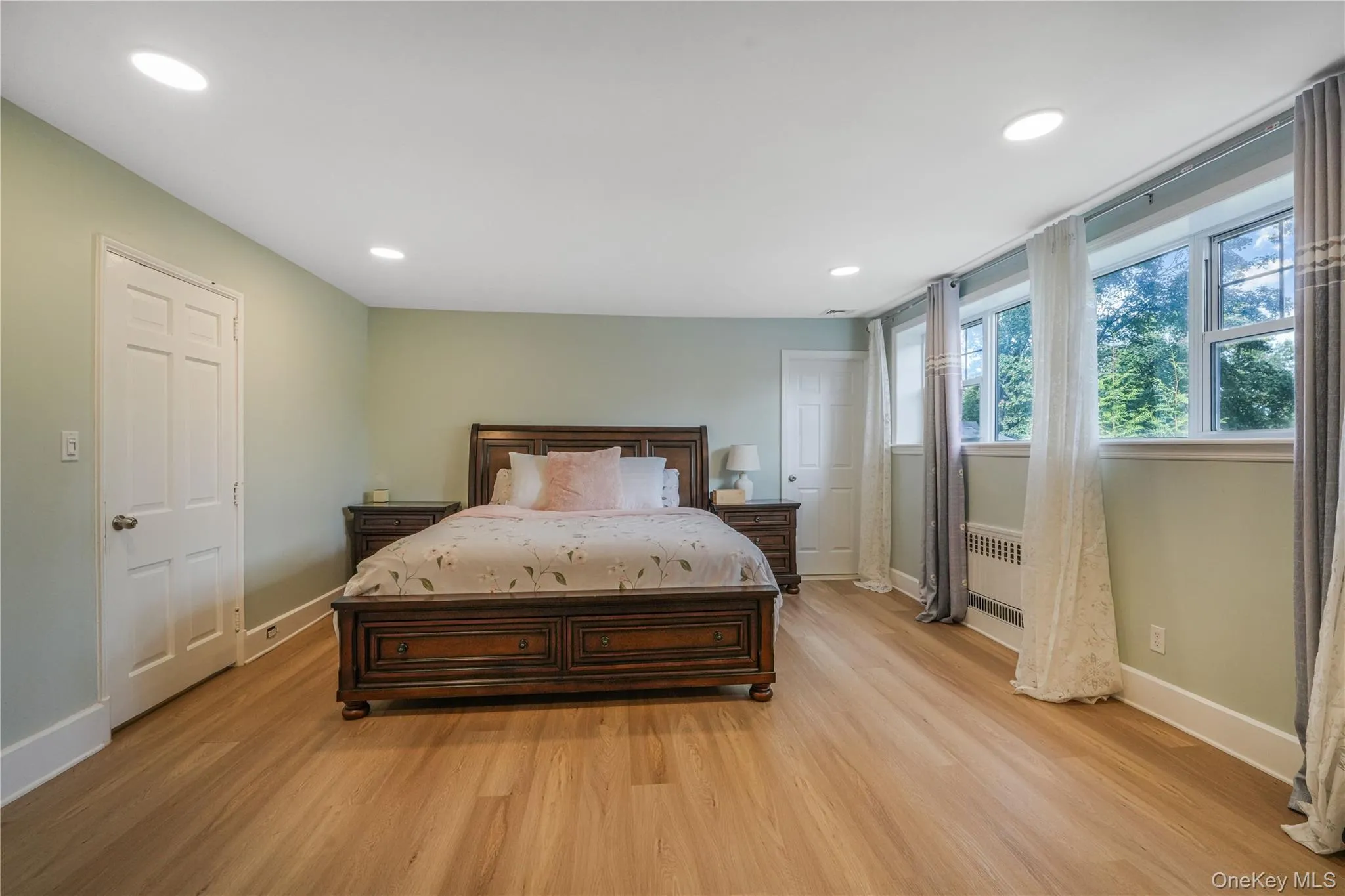 Bedroom featuring light wood-style floors, recessed lighting, and radiator heating unit Bedroom featuring light wood-style floors, recessed lighting, and radiator heating unit