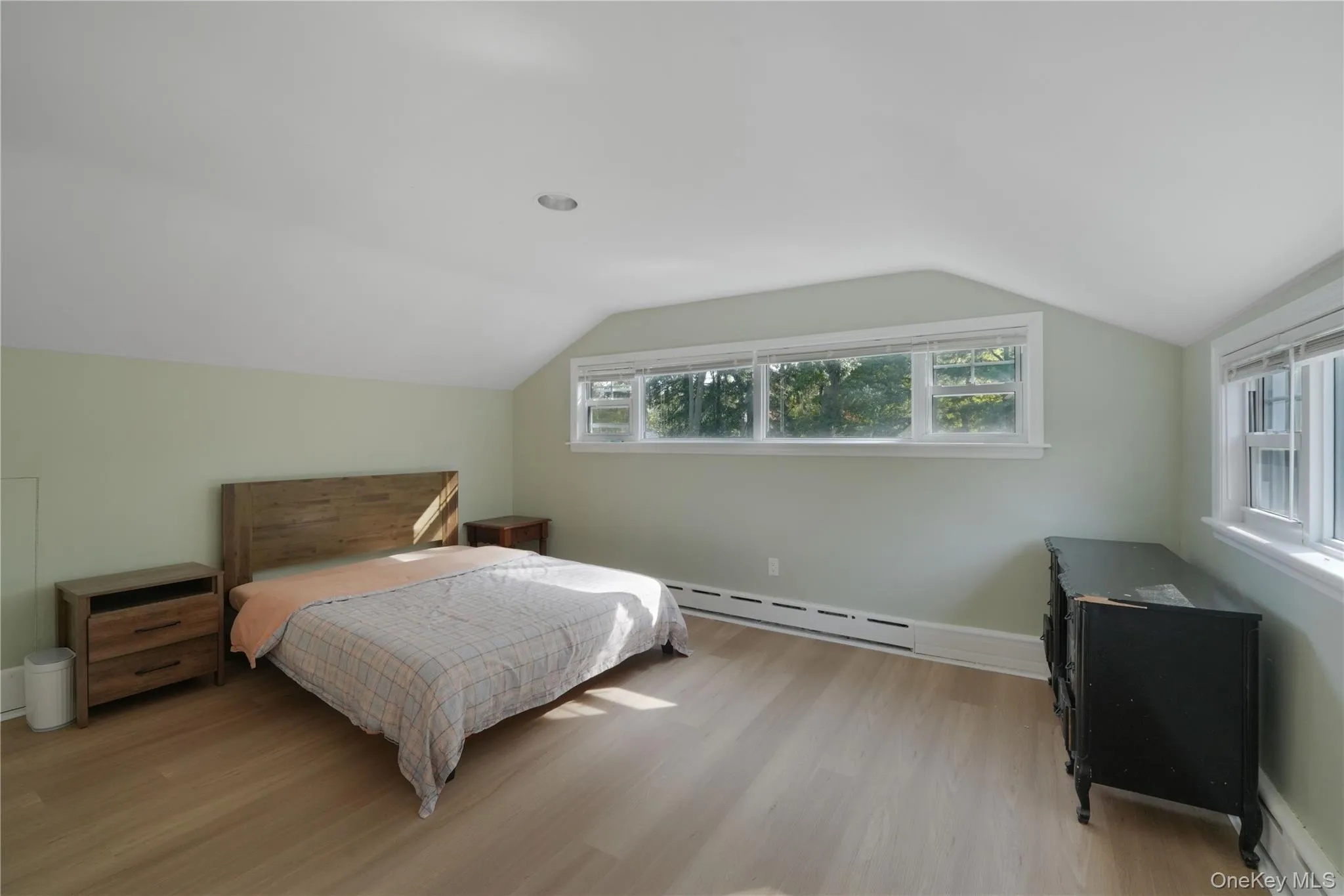 Bedroom with lofted ceiling, light wood-type flooring, and baseboard heating Bedroom with lofted ceiling, light wood-type flooring, and baseboard heating
