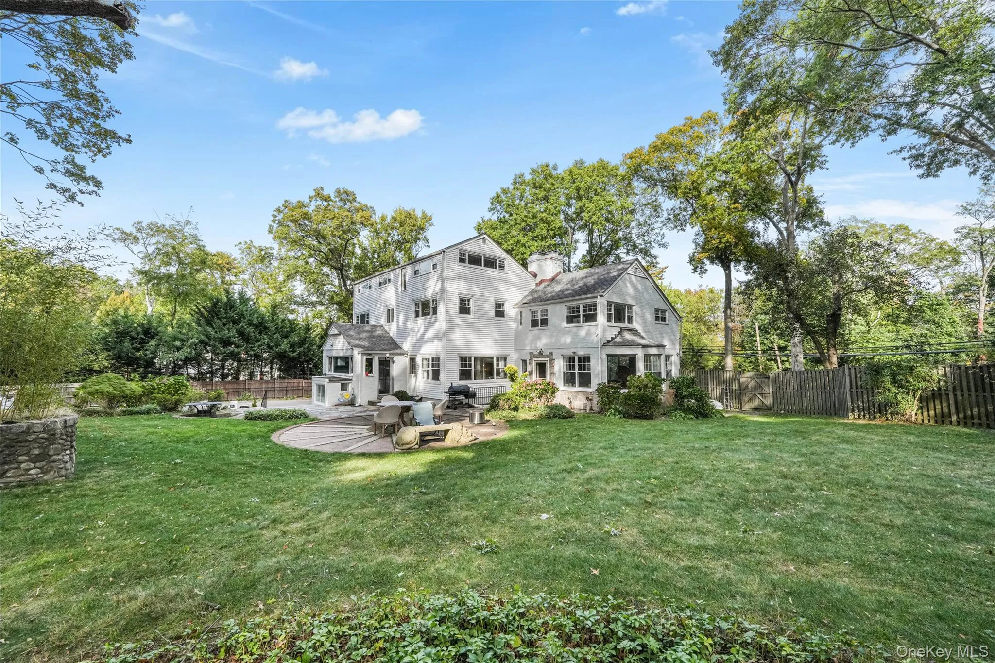 Rear view of house with a fenced backyard, a patio area, view of wooded area, and a chimney Rear view of house with a fenced backyard, a patio area, view of wooded area, and a chimney