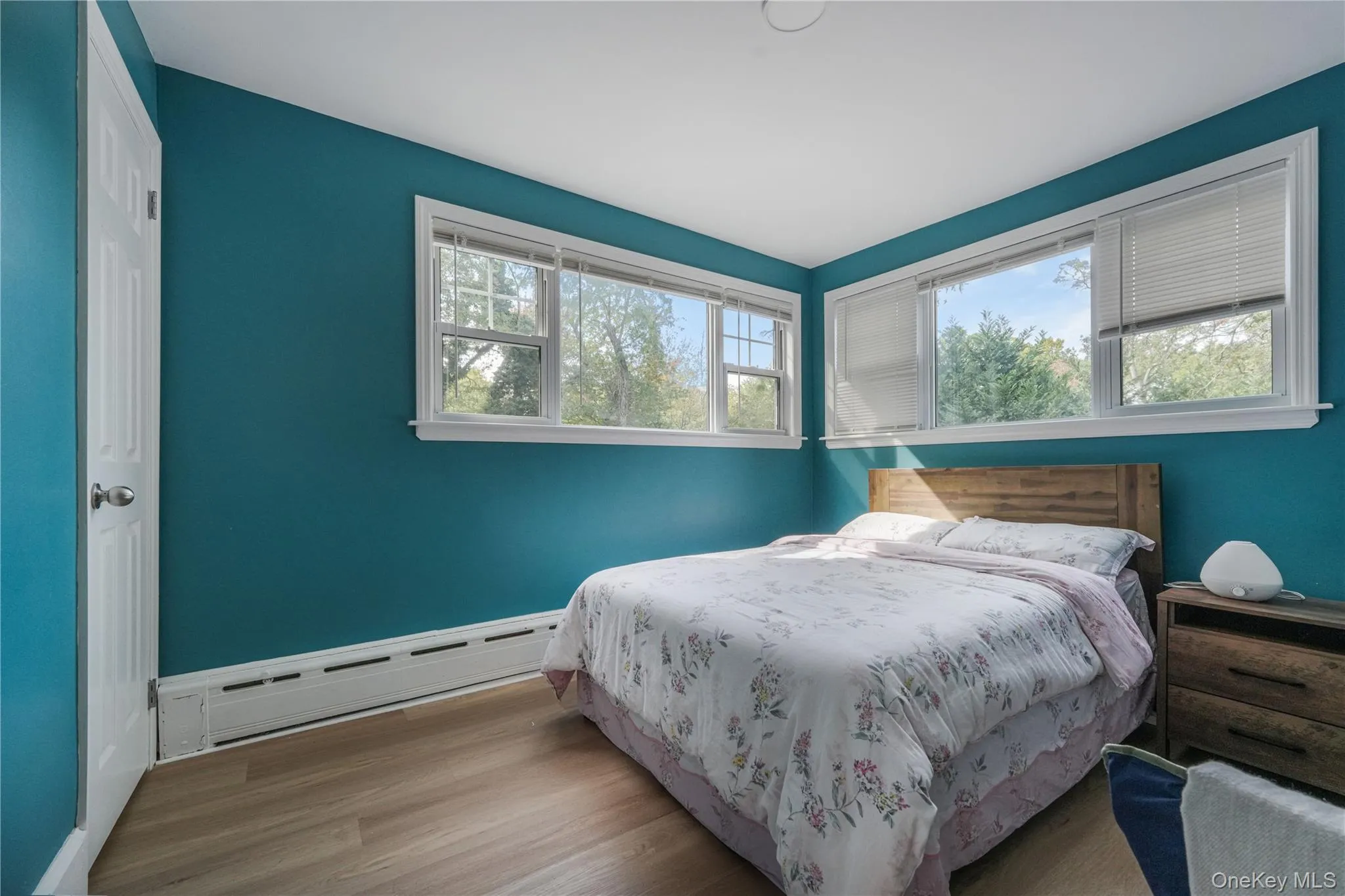 Bedroom with wood finished floors and a baseboard heating unit Bedroom with wood finished floors and a baseboard heating unit