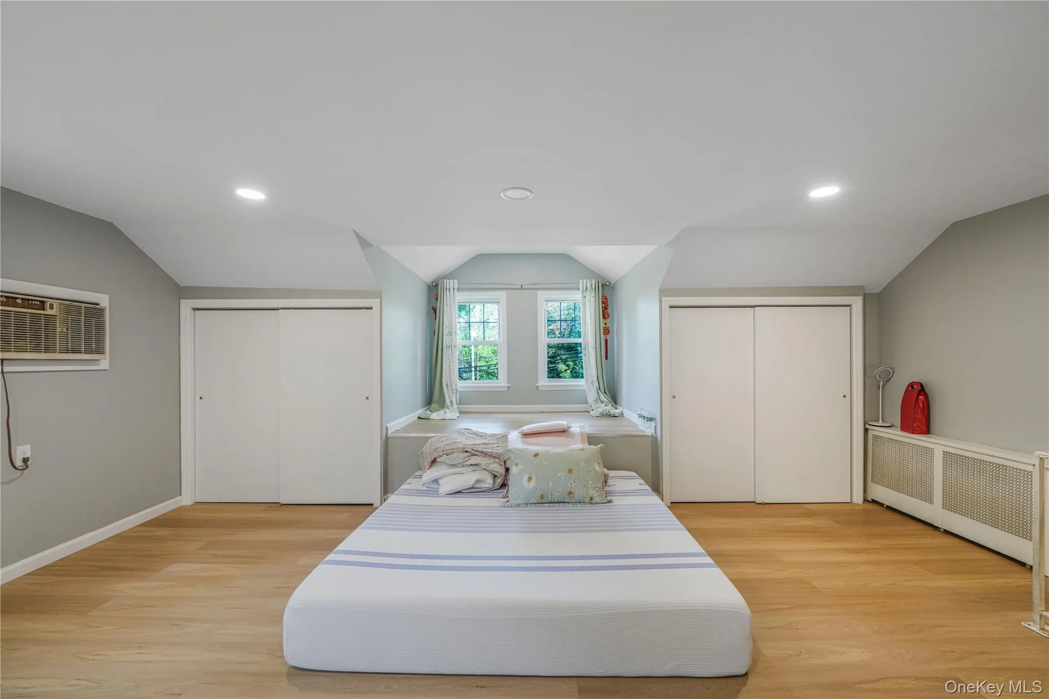 Bedroom with multiple closets, radiator heating unit, lofted ceiling, recessed lighting, and light wood-type flooring Bedroom with multiple closets, radiator heating unit, lofted ceiling, recessed lighting, and light wood-type flooring
