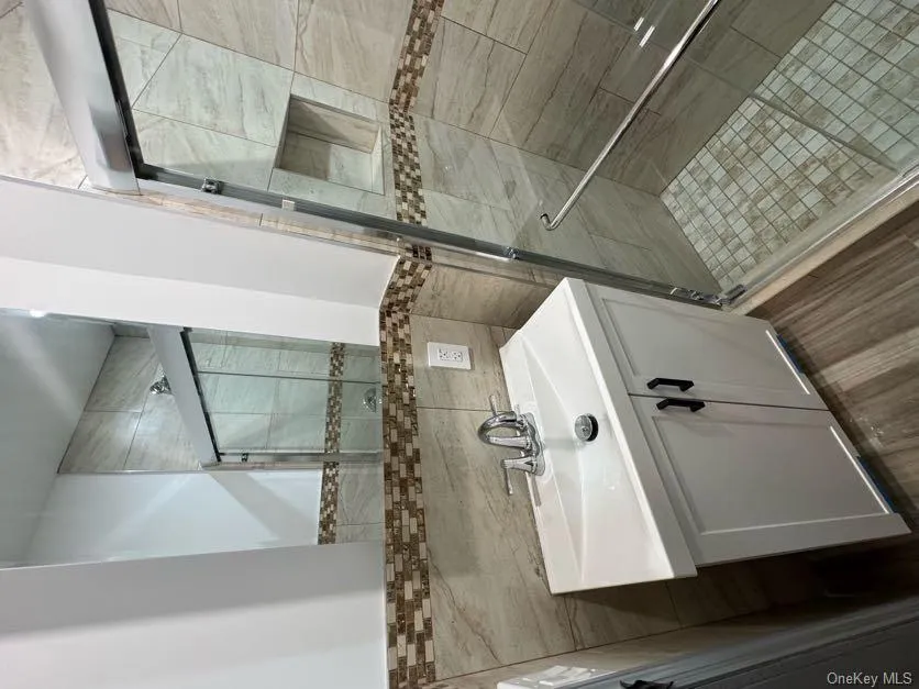 Bathroom with vanity, a stall shower, tile walls, and dark wood finished floors Bathroom with vanity, a stall shower, tile walls, and dark wood finished floors