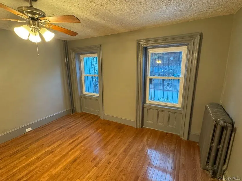 Doorway featuring radiator, a textured ceiling, hardwood / wood-style flooring, and ceiling fan Doorway featuring radiator, a textured ceiling, hardwood / wood-style flooring, and ceiling fan