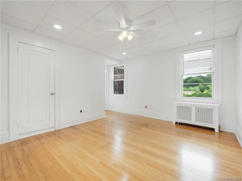 Unfurnished room featuring a drop ceiling, radiator, ceiling fan, light wood-style floors, and recessed lighting Unfurnished room featuring a drop ceiling, radiator, ceiling fan, light wood-style floors, and recessed lighting