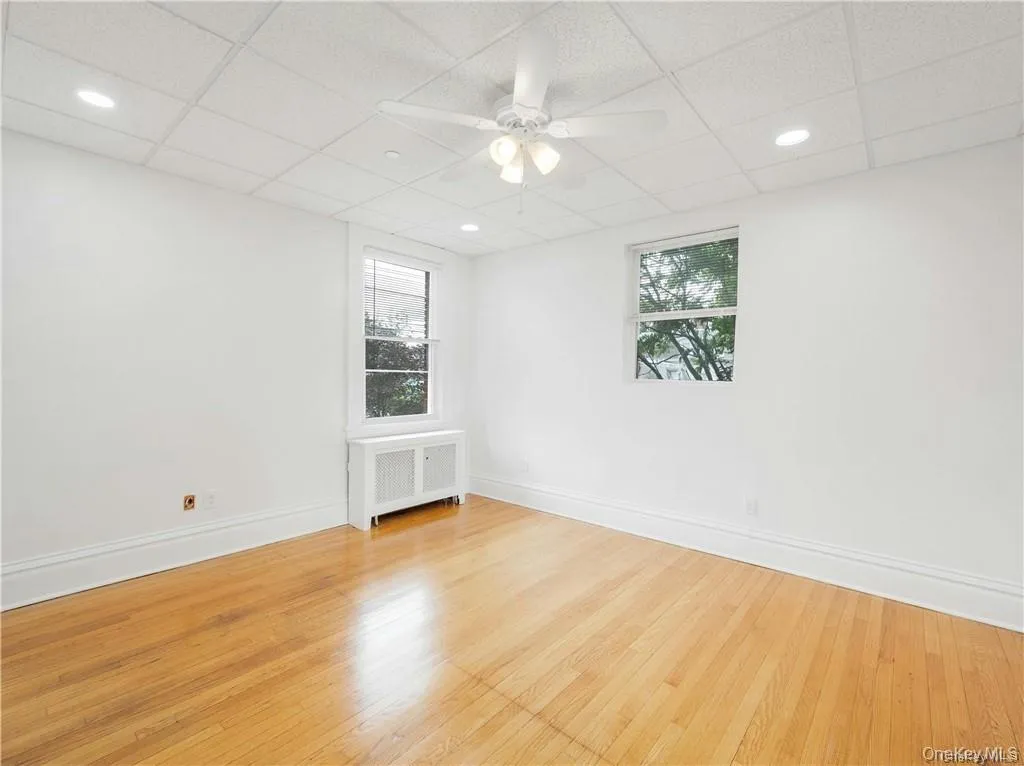 Empty room featuring radiator, a ceiling fan, light wood-style floors, a paneled ceiling, and recessed lighting Empty room featuring radiator, a ceiling fan, light wood-style floors, a paneled ceiling, and recessed lighting