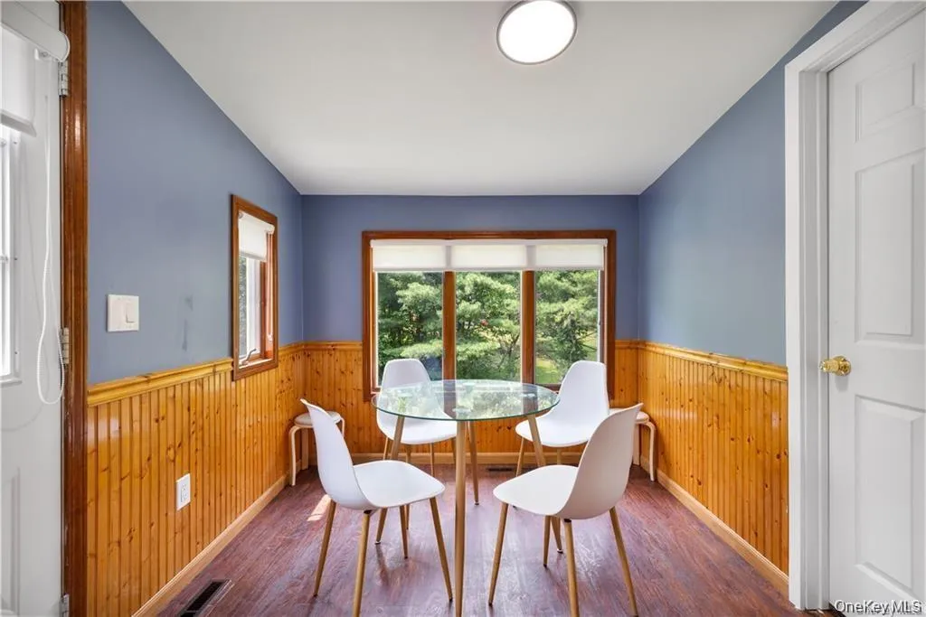 Dining room with wooden walls, wood finished floors, and a wainscoted wall Dining room with wooden walls, wood finished floors, and a wainscoted wall