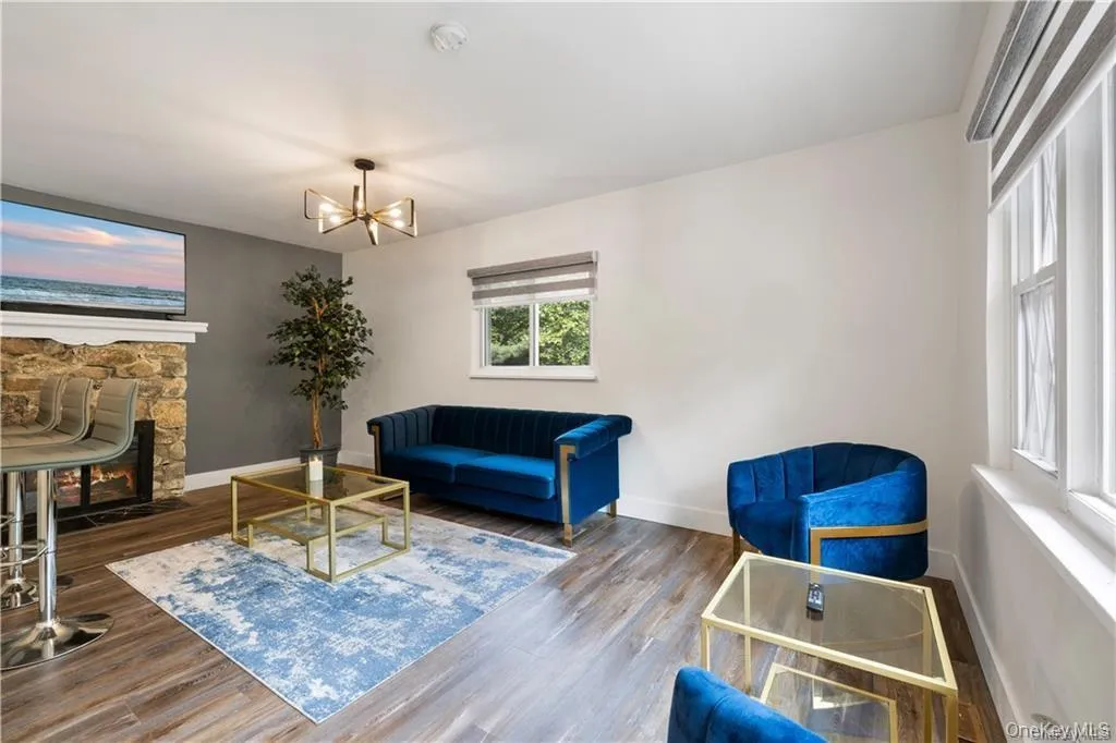 Sitting room with a stone fireplace, wood finished floors, and a chandelier Sitting room with a stone fireplace, wood finished floors, and a chandelier