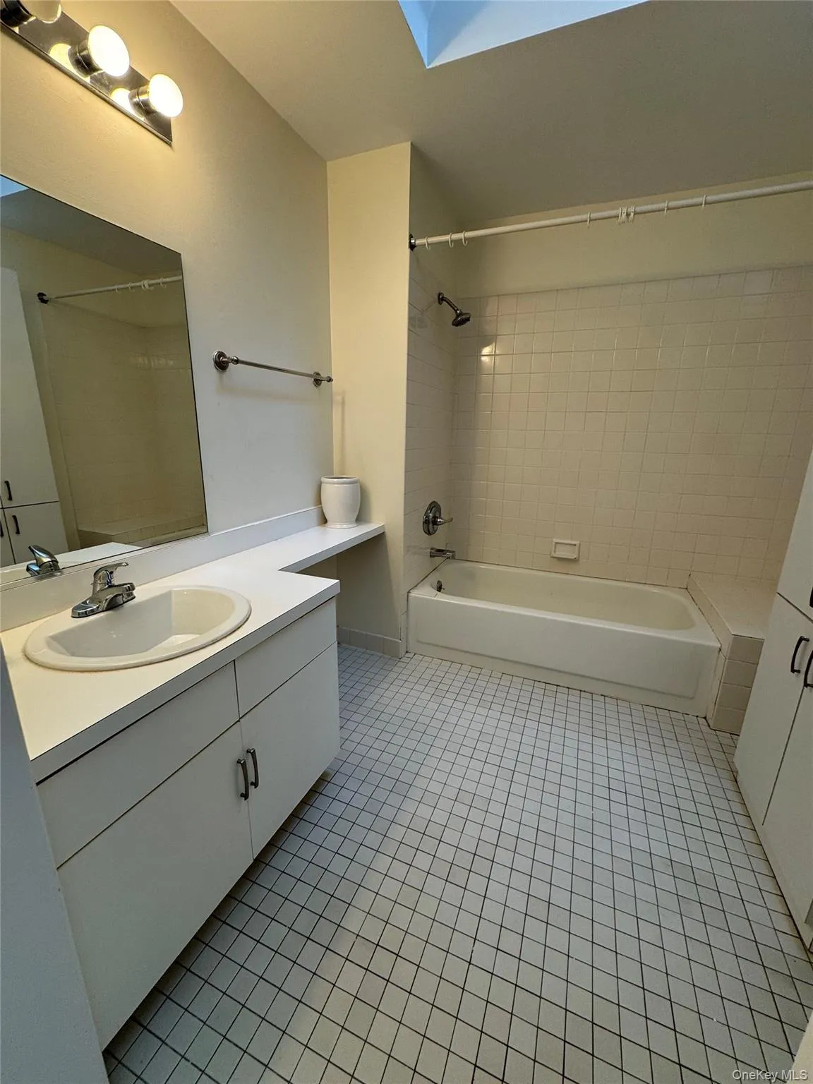 Bathroom featuring light tile patterned flooring, vanity, shower / tub combination, and a skylight Bathroom featuring light tile patterned flooring, vanity, shower / tub combination, and a skylight