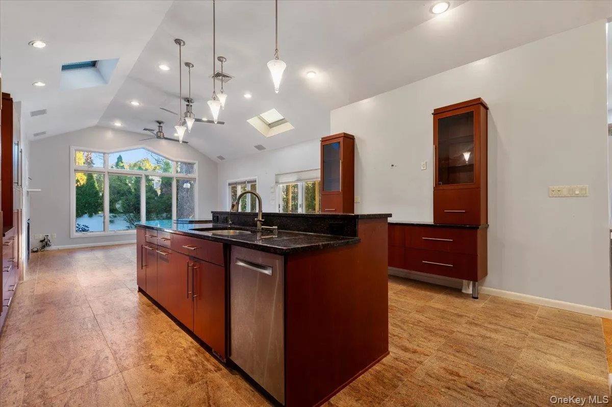 Kitchen featuring an island with sink, modern cabinets, lofted ceiling, a skylight, and pendant lighting Kitchen featuring an island with sink, modern cabinets, lofted ceiling, a skylight, and pendant lighting