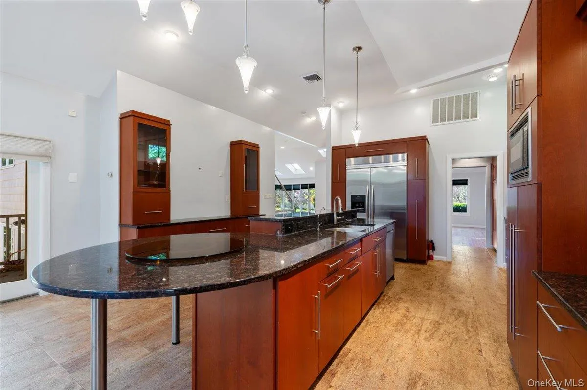 Kitchen featuring dark stone counters, hanging light fixtures, a kitchen bar, healthy amount of natural light, and recessed lighting Kitchen featuring dark stone counters, hanging light fixtures, a kitchen bar, healthy amount of natural light, and recessed lighting