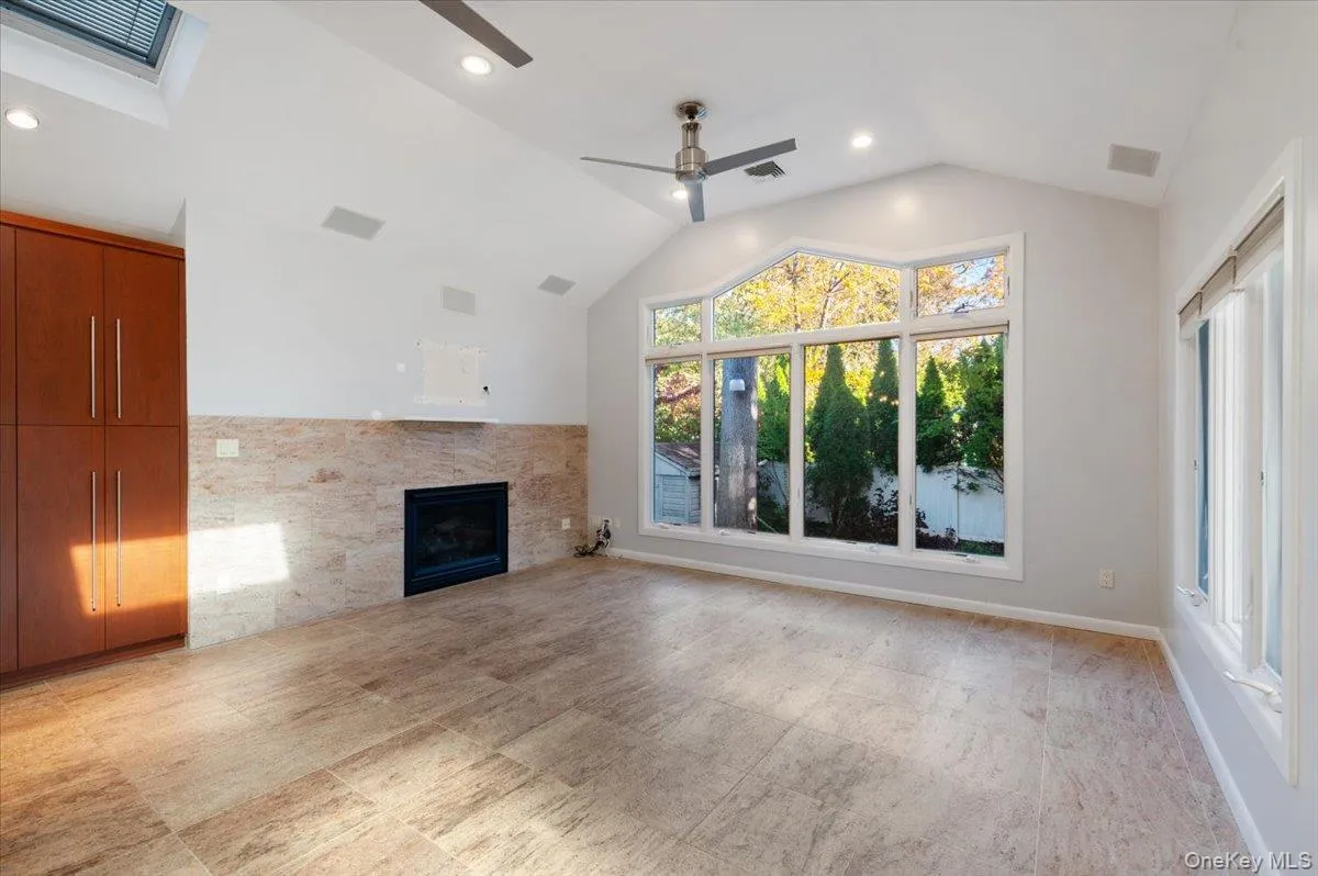 Unfurnished living room with lofted ceiling, a tile fireplace, a ceiling fan, and recessed lighting Unfurnished living room with lofted ceiling, a tile fireplace, a ceiling fan, and recessed lighting