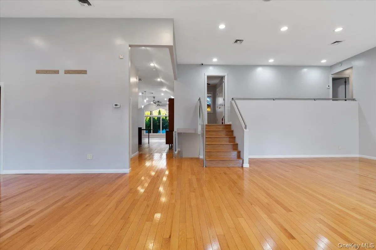 Unfurnished living room with light wood-type flooring, recessed lighting, and stairway Unfurnished living room with light wood-type flooring, recessed lighting, and stairway