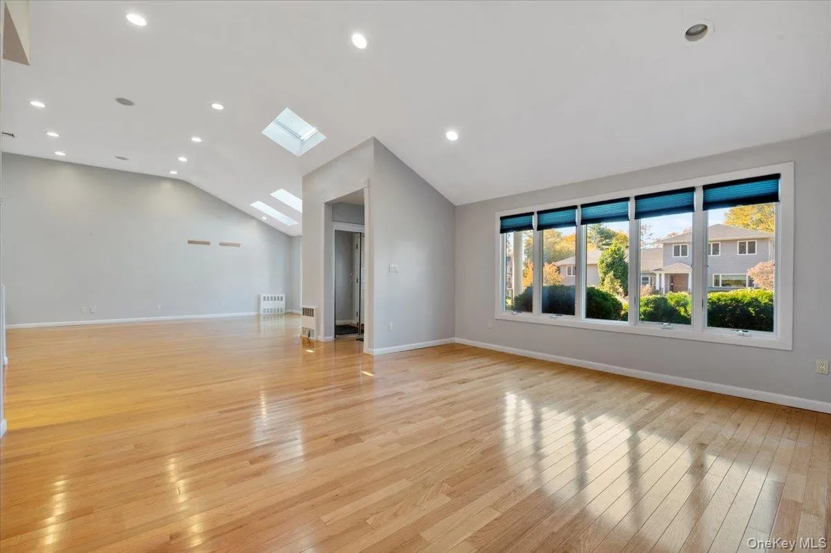 Unfurnished living room featuring recessed lighting, a skylight, light wood-type flooring, and vaulted ceiling Unfurnished living room featuring recessed lighting, a skylight, light wood-type flooring, and vaulted ceiling