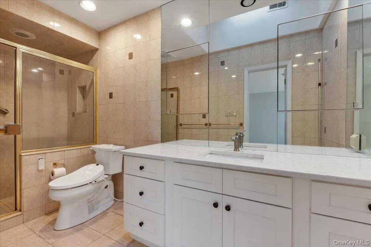 Bathroom with tile walls, vanity, light tile patterned floors, a stall shower, and recessed lighting Bathroom with tile walls, vanity, light tile patterned floors, a stall shower, and recessed lighting