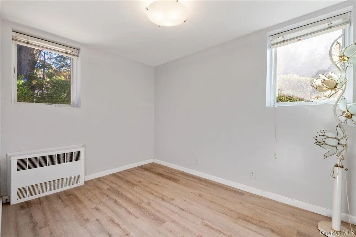 Unfurnished room featuring radiator heating unit and light wood-style flooring Unfurnished room featuring radiator heating unit and light wood-style flooring