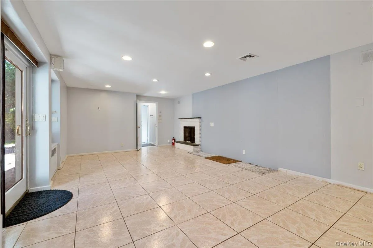 Unfurnished living room with recessed lighting, light tile patterned flooring, and a brick fireplace Unfurnished living room with recessed lighting, light tile patterned flooring, and a brick fireplace