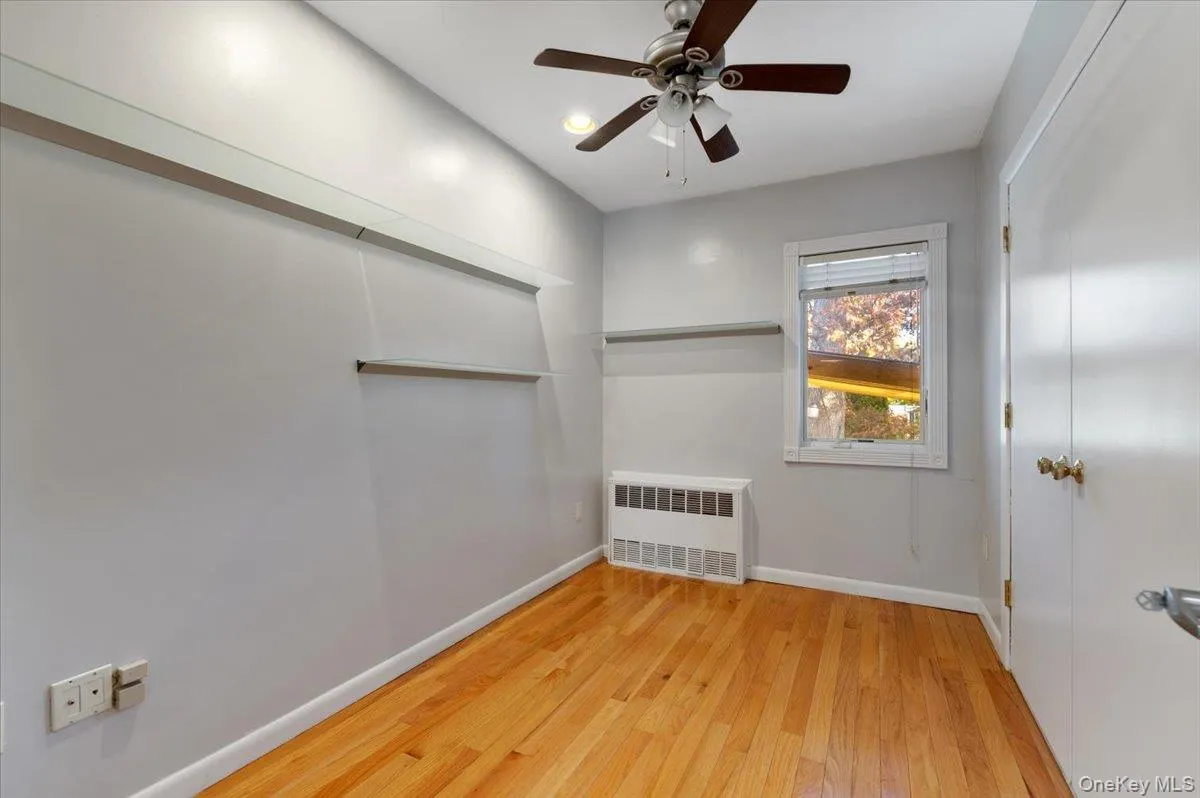 Spare room featuring light wood-style flooring, radiator heating unit, ceiling fan, and recessed lighting Spare room featuring light wood-style flooring, radiator heating unit, ceiling fan, and recessed lighting