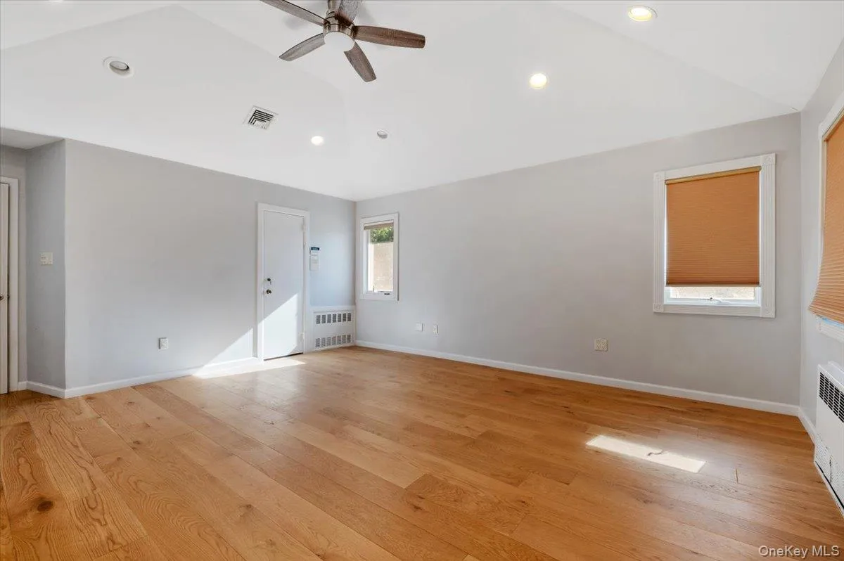 Unfurnished bedroom featuring vaulted ceiling, light wood-style floors, recessed lighting, a ceiling fan, and radiator heating unit Unfurnished bedroom featuring vaulted ceiling, light wood-style floors, recessed lighting, a ceiling fan, and radiator heating unit