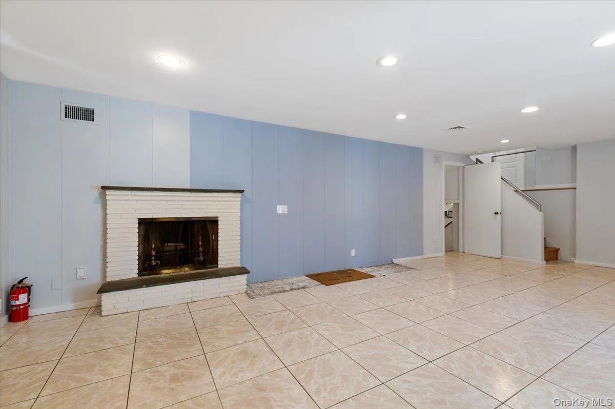 Unfurnished living room featuring recessed lighting, a brick fireplace, and light tile patterned floors Unfurnished living room featuring recessed lighting, a brick fireplace, and light tile patterned floors