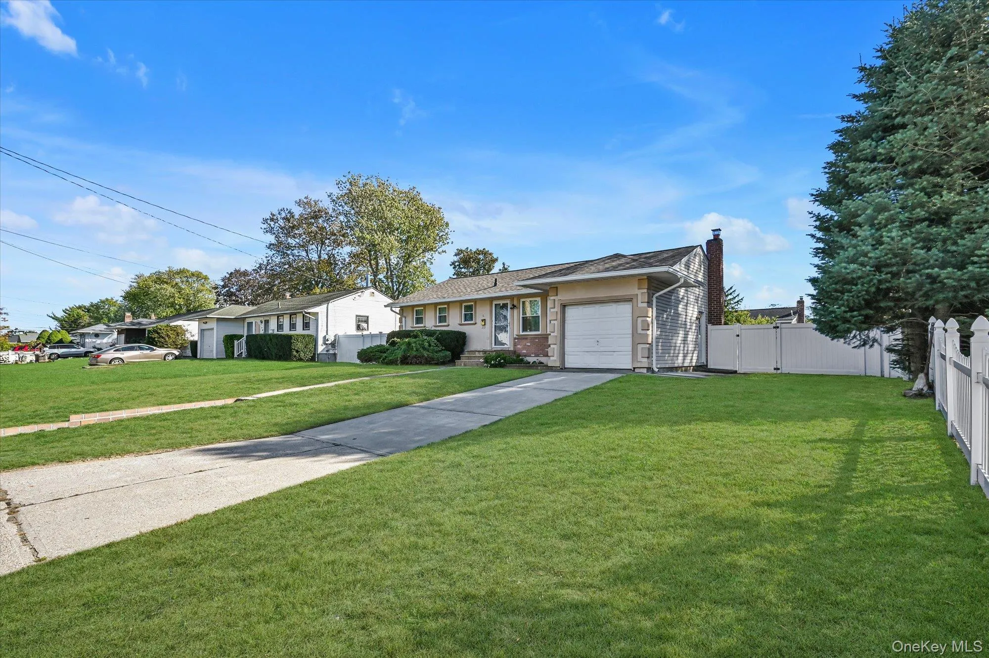 Ranch-style home with a chimney, concrete driveway, brick siding, an attached garage, and a gate Ranch-style home with a chimney, concrete driveway, brick siding, an attached garage, and a gate
